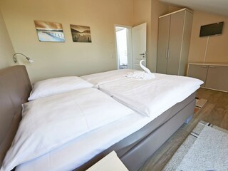 Schlafzimmer mit Doppelbett und TV