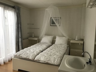 Elegantes Schlafzimmer mit weisses Bett, und Tageslicht