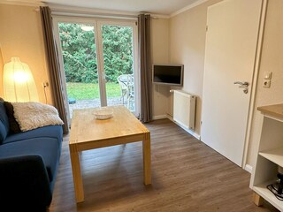 Wohnzimmer mit Couch, TV und Zugang zur eigenen Terrasse