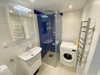 modernes Badezimmer mit WC, Waschmaschine und Dusche