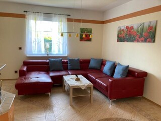 Das geräumige Wohnzimmer mit Schlafcouch und großem TV