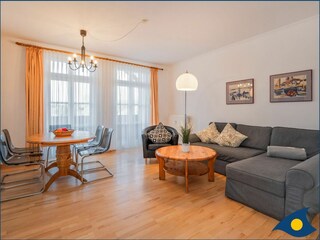 Wohnzimmer mit offener Küche und Zugang zum Balkon