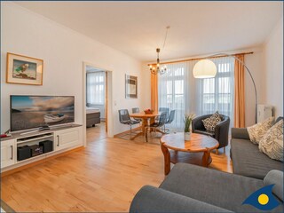 Wohnzimmer mit offener Küche und Zugang zum Balkon