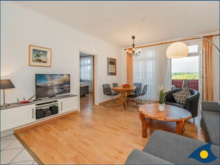 Wohnzimmer mit offener Küche und Zugang zum Balkon