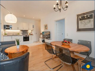 Wohnzimmer mit offener Küche und Zugang zum Balkon