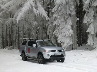 Mit dem Geländewagen durch den verschneiten Hochwald.
