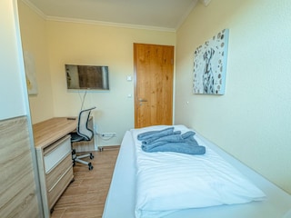 Einzelbett-Schlafzimmer im ersten OG mit Schreibtisch und Fernseher