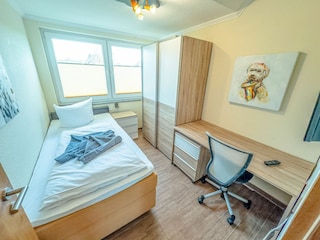 Einzelbett-Schlafzimmer im ersten OG mit Schreibtisch und Fernseher