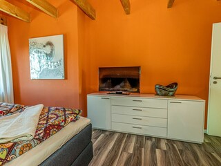 Gemütliches Schlafzimmer mit sichtbaren Deckenbalken, Fernseher und gemütlichem Doppelbett