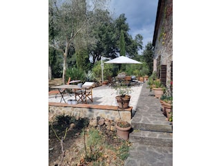 Terasse mit Sonnenschirm, Tischen und Sitzmöglichkeiten