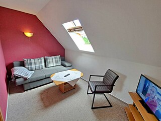 Wohnzimmer im 1. OG mit Couch (Schlaffunktion, Aufbettungsmöglichkeit für 2 weitere Personen), TV