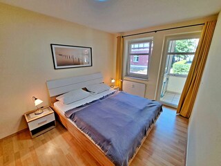 Schlafzimmer mit Doppelbett und Zugang zum Wintergarten