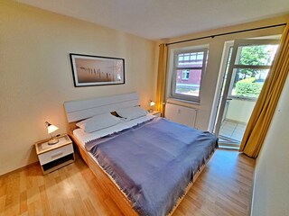 Schlafzimmer mit Doppelbett und Zugang zum Wintergarten