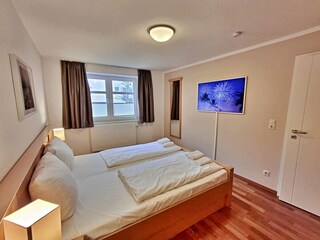 Schlafzimmer mit Doppelbett und hochwertigem Frame-TV