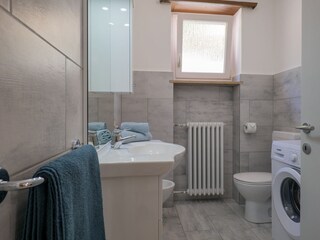 Freundliches Badezimmer mit Dusche, Waschmaschine und Fenster