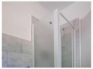 Freundliches Badezimmer mit Dusche, Waschmaschine und Fenster