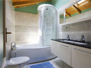 Freundliches, modernes Badezimmer mit Badewanne und integrierter Dusche sowie Fenster