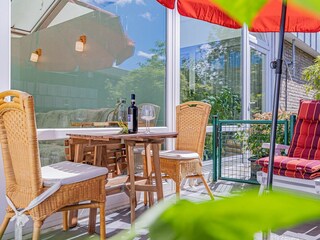 Sonnige Terrasse mit Gartenmöbeln und Sonnenliegen