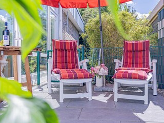 Sonnige Terrasse mit Gartenmöbeln und Sonnenliegen