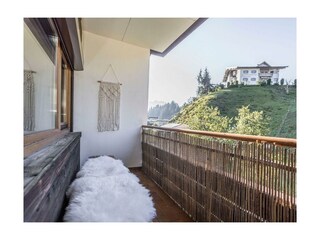 Balkon mit Sitzbank und Gartenblick.