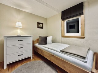 Schlafzimmer im OG mit Einzelbett und Kommode