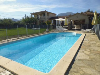 Blick vom Pool auf die Villa dahinter Bergpanorama