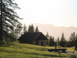 Wanderer mit Brunnen und Hütte Holzalm Brixlegg So