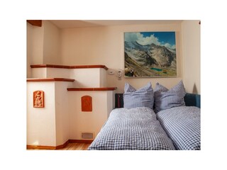 Stube mit Bett und Kachelofen