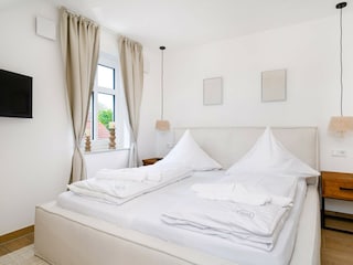 Schlafzimmer mit Doppelbett und TV