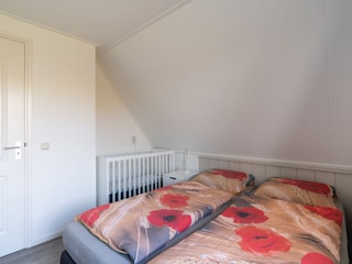 Schlafzimmer mit 2 Einzelbetten und einem Kinderbett