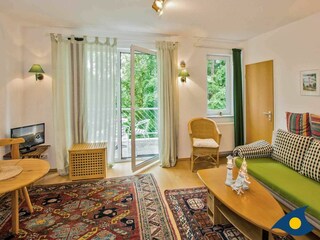 Wohnzimmer mit Schlafcouch und Zugang zum Balkon