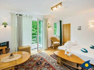 Wohnzimmer mit Schlafcouch, Essbereich und Zugang zum Balkon