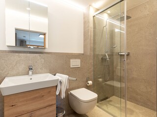 Erstes Badezimmer mit ebenerdiger Dusche und Steinboden