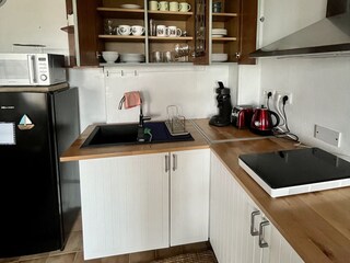 Kitchen corner with induction hob, microwave and fridge