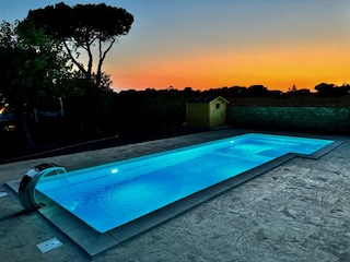 Beleuchteter Pool mit Wasserfall.
