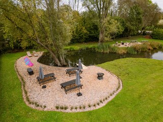 Der Schwimmteich mit Gartentischen und Liegestühlen