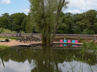 Der Schwimmteich mit Gartentischen und Liegestühlen
