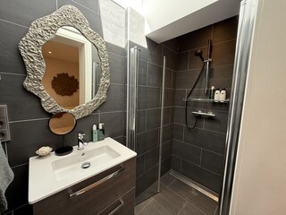 Badezimmer mit Waschbecken, Spiegel und Toilette.