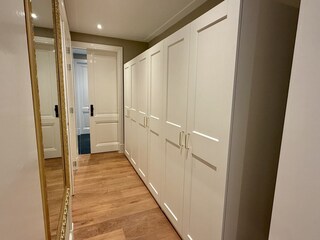 Schlafzimmer mit Holzschrank und sanfter Beleuchtung.