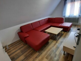 zweites Wohnzimmer mit großer Couch und TV