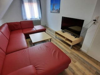 zweites Wohnzimmer mit großer Couch und TV