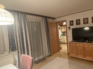 Wohn-Esszimmer mit Balkon und großen TV-Bildschirm