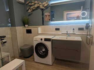 Badezimmer mit WC, Waschbecken und Waschmaschine