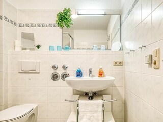 Badezimmer mit WC, Waschbecken, Spiegel und Dusche