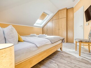 Schlafzimmer mit Doppelbett, Kleiderschrank und TV