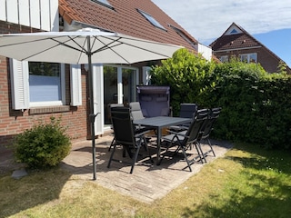 Terrasse mit Strandkorb, Gartenmöbeln und Sonnenschirm