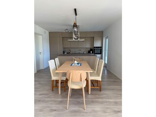 Esstisch mit dahinterliegender Küche