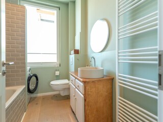 Badezimmer mit Waschmaschine und Badewanne