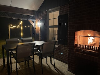 Überdachte Veranda mit Kamin und stimmungsvoller Garten