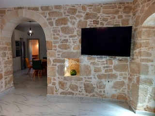 Wohnzimmer mit TV und Blick in die Küche